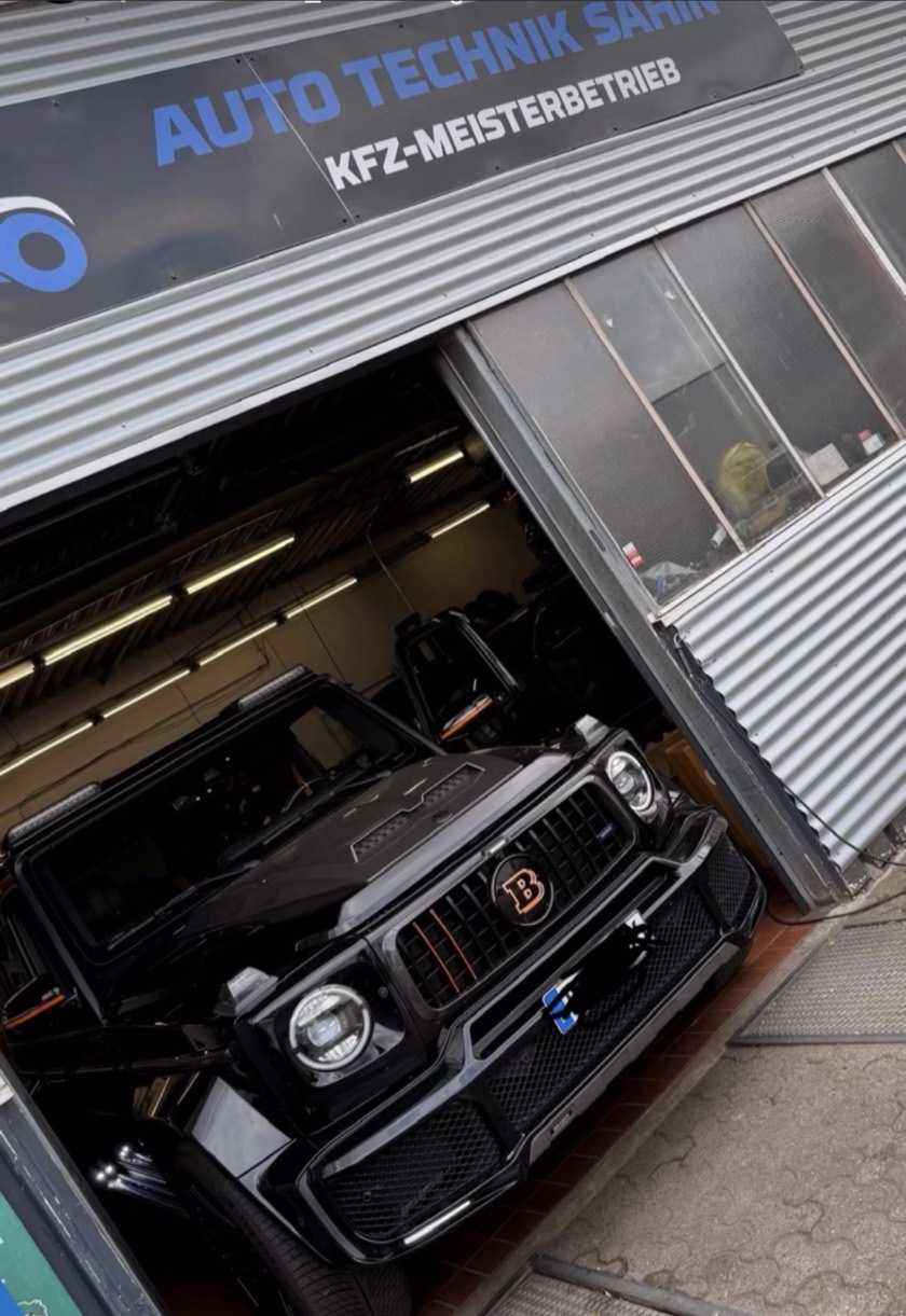 In der Werkstatthalle von Auto Technik Sahin in Kamp-Lintfort steht ein schwarzer, Brabus-umgebauter Mercedes G-Klasse unter dem Hallenschild „Auto Technik Sahin – KfZ-Meisterbetrieb“.